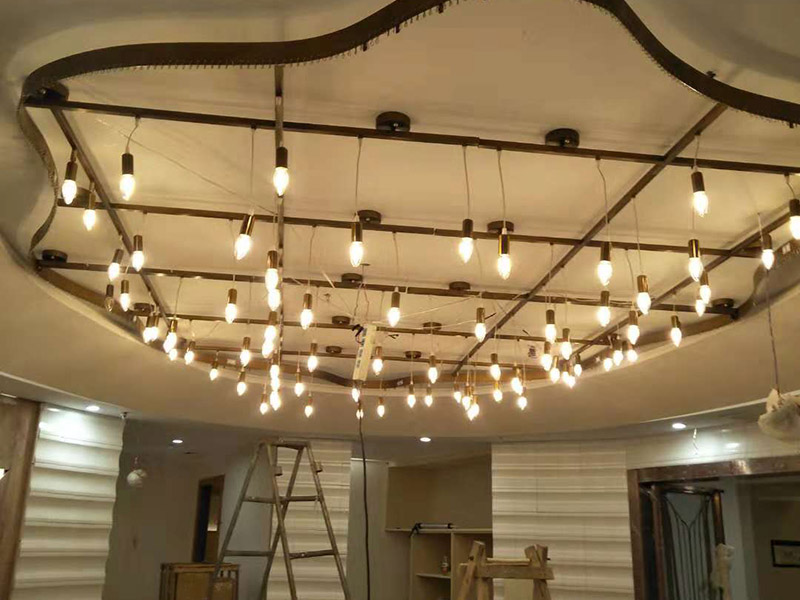 大型吊燈安裝：首先大致尺寸要測量好，確定位置；然后石膏板上鉆孔，然后埋設(shè)鐵件五金配件或者木條，用黏貼劑或者水泥漿將空洞的周邊補(bǔ)齊，等到差不多干燥了再接下來做。接著把鐵件或者木條固定，這是吊燈安裝的重要步驟，如果沒有固定好，使用壽命會受到影響。電線通過吊桿引入到燈芯里面，如果配套燈帶使用開關(guān)的，穿線的時候要注意線路的走向。最后就是燈罩、燈臂的安裝。用看、螺絲刀等工具將燈罩組裝好，安裝好后，通電試試就可以了，根據(jù)實際情況稍微調(diào)整下。