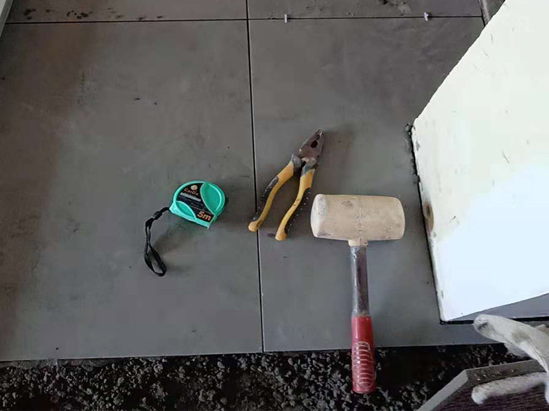 客廳地磚鋪貼：鋪貼的工具包括橡膠錘和粘結(jié)劑。在進(jìn)行施工之前先把所需要的這些材料都整理好放在一旁備用；基層的處理工作對瓷磚的平整度有很大的影響，對于基層要做好清潔工作，還有找平工作。放樣：在進(jìn)行瓷磚的鋪貼工作之前還事先找好垂直線，這樣可以在鋪貼的時(shí)候找到瓷磚的水平線，讓瓷磚鋪貼的更加的平整。粘結(jié)劑加水?dāng)嚢杈鶆?，靜置10分鐘之后就可以使用。將瓷磚表面的浮灰清除，再在瓷磚背面均勻的涂抹上粘結(jié)劑，按照預(yù)鋪的順序?qū)⒋纱u鋪貼在地面上，最后用橡膠錘輕輕拍打至服帖齊整。