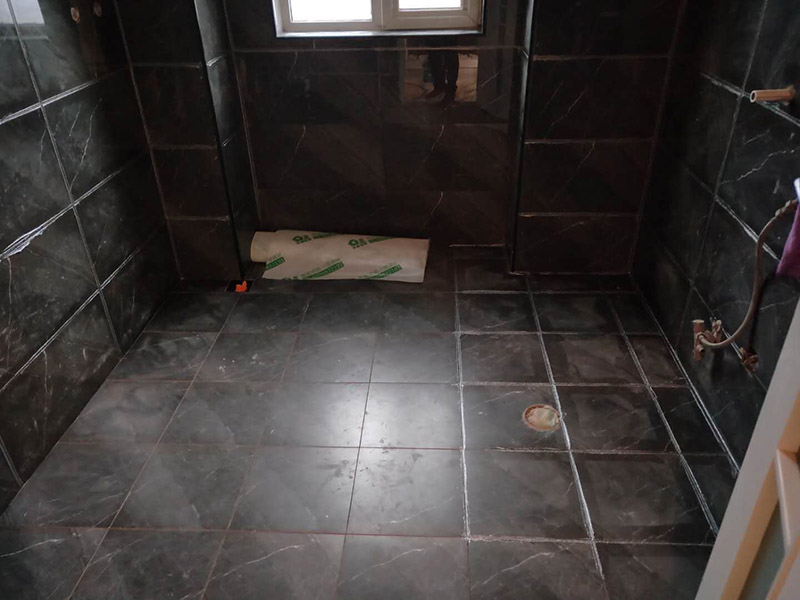 衛(wèi)生間美縫施工：使用用開槽器/平口螺絲刀/勾縫刀，清理瓷磚縫隙內(nèi)灰塵及垃圾，這一步需要力度適中，不要用蠻力，不然可能存在崩壞瓷磚的風(fēng)險(xiǎn)。然后用吸塵器，掃把或者抹布清理干凈。，建議縫隙在1.5到2mm深度合適。縫隙清理干凈后， 擰開管蓋裝上混合管，管頭卡在膠槍的卡口上。裝好混合管后，從下方用美工刀斜切45度角，切記開口要比瓷磚縫隙小，如果本身瓷磚縫隙比較小，可以不用切膠嘴。首先打出30-40CM美縫劑余料，然后沿著瓷磚縫隙開始施工，在施工的時(shí)候一定要美縫劑填充滿瓷磚縫隙，不然后續(xù)可能會(huì)發(fā)生塌陷。瓷磚縫隙打膠方法先豎后橫，沿著縫隙均勻打出美縫劑.一般有些師傅打出3-5米時(shí)停下，開始用壓邊球壓縫，十字交叉口處多壓幾次，這樣會(huì)很美觀。壓縫的工具比較多，可用刮板或者壓縫 鋼球、手指套沿著縫隙壓出 U型面就可以了