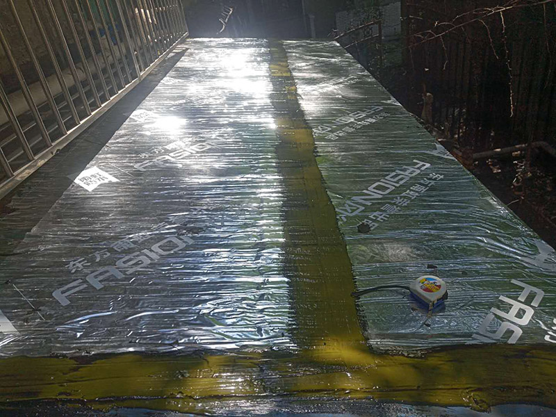 雨棚防水施工：1、待軟性防水層充分冷卻后，將塑料彩條棚布鋪設(shè)其上形成浮筑層(兩塊棚布須重疊)，起剛性水泥層和軟性防水層滑動間隔用。 2、鋪設(shè)5厘米厚的細(xì)石混凝土，內(nèi)用4毫米直徑的鐵絲結(jié)成孔徑小于10&times;10厘米的鐵絲網(wǎng)，加強(qiáng)混凝土的抗拉力。 3、剛性水泥層與女兒墻、立墻間留分格縫，可有效地防止其開裂。 4、大面積屋頂須設(shè)置分格縫，縫隙2厘米，鋼筋在分格縫必須分開。混凝土充分干透后，分格縫內(nèi)清掃干凈，并填充防水油膏。分格縫因順坡度設(shè)置并錯開軟性防水層接縫。因分格縫的防水質(zhì)量難保證，必須嚴(yán)格操作。 5、剛性層鋪設(shè)時，表面必須形成坡度，加快積水排出屋面。 整個防水屋面鋪設(shè)完畢后，防水層由七層組成：防水油膏、油毛氈、防水油膏、油毛氈、防水油膏、塑料彩條棚布、混凝土。