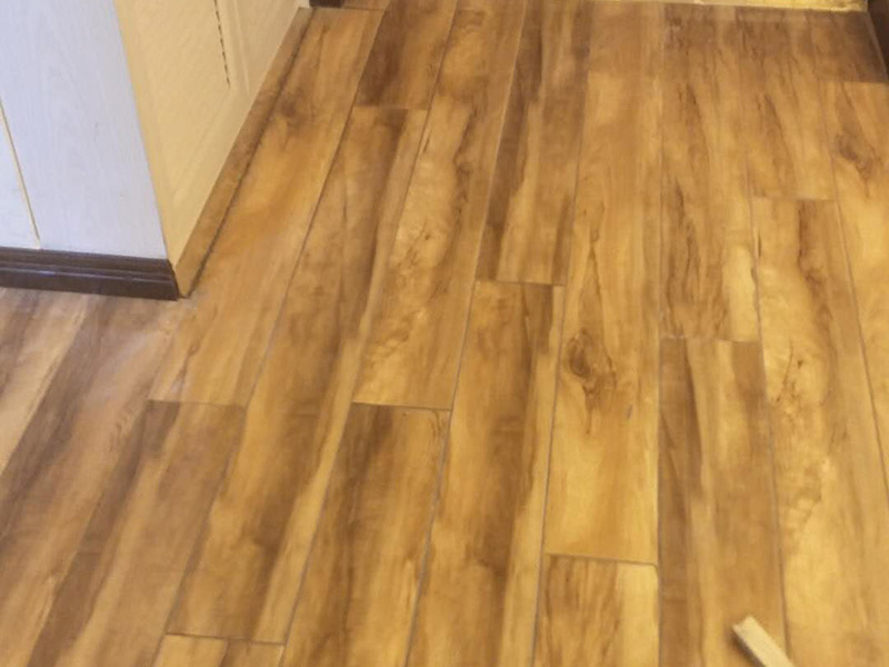 入戶門鋪地板：1、先對(duì)地面進(jìn)行找平，水平的誤差不能超過(guò)2毫米。地面要是不平，腳感就不好。再就是將邊、角部位等突起或有不平的地方進(jìn)行局部修整。再鋪防潮層，防潮層可以防止以后地板受潮。鋪平，接縫處要并攏。  2、然后就是安裝地板了，因?yàn)榈匕迨且e(cuò)落安裝的，先預(yù)鋪一下，將部分地板一分為二，要按尺寸來(lái)鋸，萬(wàn)一鋸多了，地板損耗就大了。因?yàn)榈匕逵幸欢ǖ呐蛎浡?，因此鋪裝前要在其與墻面接觸的部位預(yù)留膨脹縫，以免地板起鼓。膨脹縫的大小一般和地板的膨脹系數(shù)有關(guān)系。粘合地板的膠水要用強(qiáng)化地板專用的，這種膠的污染比較小。不要隨便在市場(chǎng)上選非地板專用膠，地板本身就存在的污染上再增加污染源。  3、鋪前看好地板是否用對(duì)，再鋪設(shè)地板。在鋪設(shè)時(shí)，要一塊短的旁邊鋪一塊長(zhǎng)的，這樣交叉鋪設(shè)地板就咬得住不易松動(dòng)，地板拼合后還要用工具敲緊。再下來(lái)就是銜接了，一般用地板壓條掩蓋。但也有用玻璃膠填充。