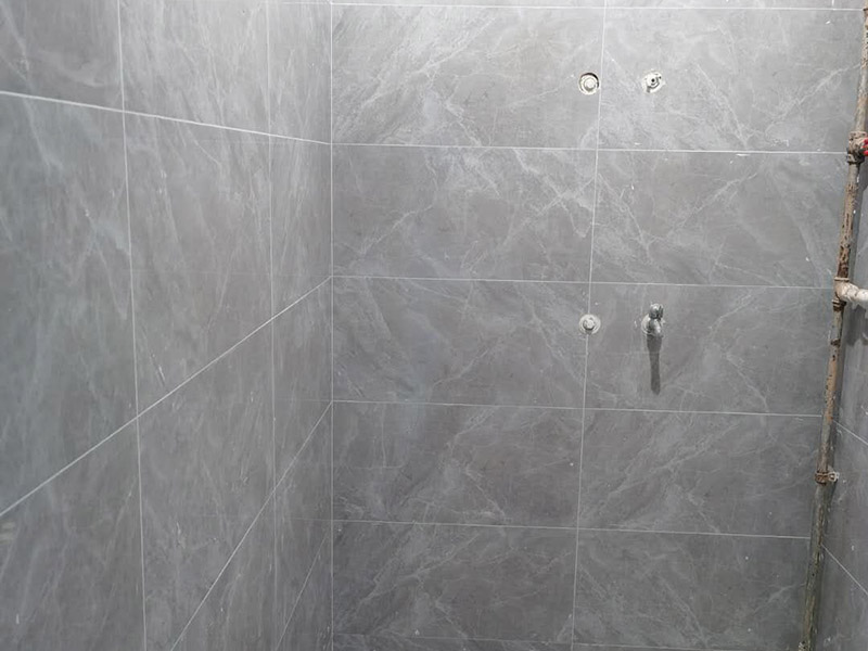 衛(wèi)生間貼磚施工：應全部清理墻面上的各類污物，打掃干凈現(xiàn)場，特別是腳落里。用泥刀先批墻，后用水泥漿找平。這個工序很重要，確保底子平，防止貼后空鼓。墻面要刷防水涂料，防止貼后浸水，一般高度不低于1.8米，刷的時候會稍高一些。根據(jù)設計鋪貼圖樣的要求，確定排磚方案，用墨斗彈線，以減少施工損耗。把剛剛攪拌好的粘結(jié)劑漿料均勻的刮到墻上。瓷磚上墻將經(jīng)過預先清潔的瓷磚平整地鋪貼在粘結(jié)劑漿料基層上，使用橡膠錘將瓷磚拍實鋪平。施工過程中，可小幅度轉(zhuǎn)動瓷磚，使?jié){料與瓷磚背面充分接觸。專家建議在鋪貼時，隨機取下已鋪貼于基層上的瓷磚作檢查。確保漿料與瓷磚背面的充分接觸。 留縫大小調(diào)整根據(jù)瓷磚的尺寸，在磚與磚之間預留相應尺寸的縫隙留待嵌縫?？捎醚篮灥认裙潭ǎ辰Y(jié)劑具有一定的可調(diào)整性，可對留縫的大小進行調(diào)整。