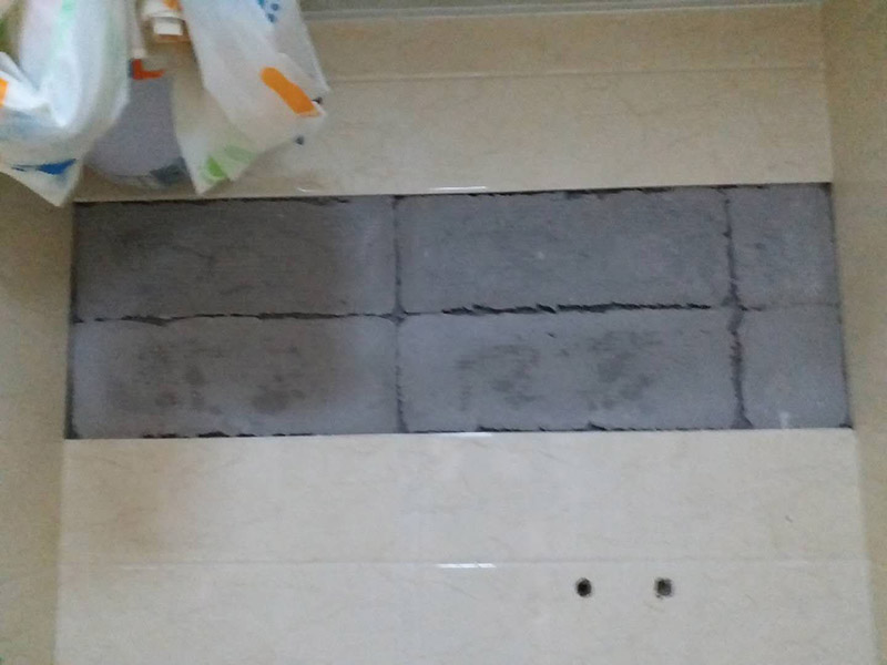 墻面瓷磚脫落修補(bǔ)：首先將脫落的磚四周用裁紙刀的刀背咔嚓一遍，將勾縫劑或水泥等附著物清理掉，漏出瓷磚的原邊。同時(shí)需要清理的，還有墻上與脫落瓷磚相連的瓷磚邊緣。當(dāng)然，用刀刃也可以，但比較毀刀片。然后用稍微潮濕的抹布擦干凈瓷磚背面的浮灰，最好用鋼絲球來刷一遍瓷磚背面再擦，目的是去掉可能存在的脫模劑。接著就是清理墻面的水泥砂漿層，將松動的碎塊去掉，然后也整體用抹布擦一遍。將玻璃膠用裁紙刀切掉密封出口，如果有槍嘴就擰上槍嘴，沒有也可以直接用。如果墻上的水泥砂漿四周有縫隙，可在縫隙內(nèi)也擠些玻璃膠，這樣可以連接那些沒掉的瓷磚，防止附近的瓷磚將來也脫落。然后將這背面抹膠的瓷磚貼回原處，磚與磚之間插上牙簽來留縫隙。再用手指抹玻璃膠到磚與磚之間的縫隙里。