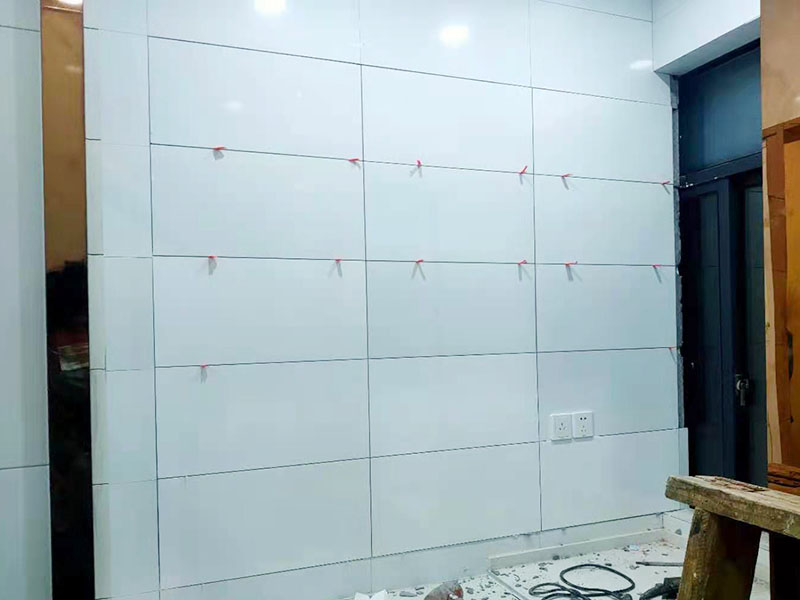 墻磚鋪貼施工：基層處理：保持墻面的平滑，踢平表面凹凸不平的位置或用1:3比例的水泥漿抹平，用鐵絲擦掉殘留的灰塵、油漬、砂漿等。 找標(biāo)高、彈線：根據(jù)水平控制線和設(shè)計(jì)圖紙劃出標(biāo)高，再拋出十字線并保持墻面一線和地面一線垂直。 預(yù)鋪：在圖紙?jiān)O(shè)計(jì)要求的基礎(chǔ)上，嚴(yán)格挑選墻磚的色彩、紋理等，然后進(jìn)行預(yù)鋪，對(duì)于預(yù)鋪效果中可能出現(xiàn)的紋理、尺寸、色差進(jìn)行調(diào)整、更換，直到達(dá)到最佳效果。 貼磚：貼磚選用1：3比例的干硬性水泥砂漿，砂漿厚度2cm左右。鋪貼前將墻磚背面濕潤(rùn)，正面保持干燥。把墻磚輕輕地放在水泥砂漿上，用手錘輕敲瓷磚表面直至緊密平整即可。 勾縫、擦縫：在貼完磚24小時(shí)后進(jìn)行勾縫工作，采用同一品種的水泥漿或?qū)Ｓ锰羁p劑進(jìn)行空隙填補(bǔ)，使墻磚最終緊密嚴(yán)實(shí)，最后再擦凈多余的水泥或填縫劑。