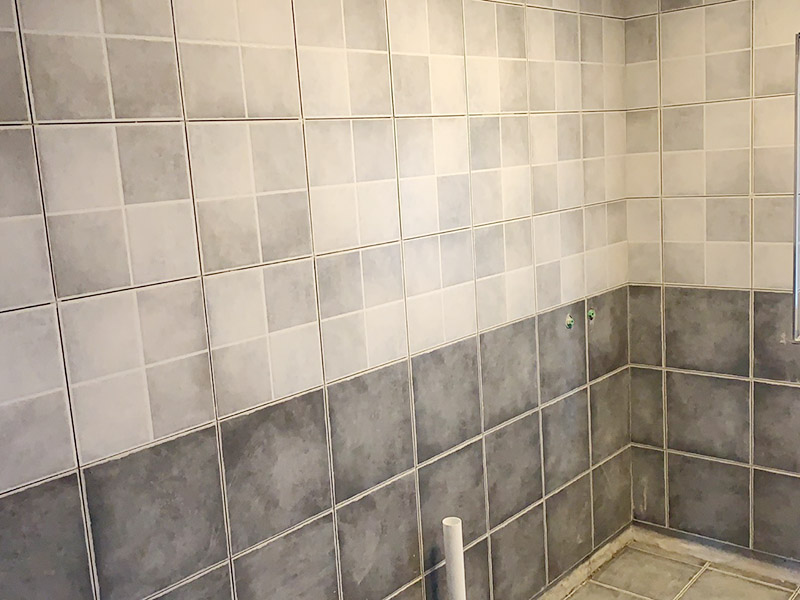 衛(wèi)生間墻磚鋪貼：首先應(yīng)除去基層表面的污垢，油漬，浮灰;除去基層上所有涂料層，膩子層;如果基層未能達到平整度要求，需對基層進行預(yù)先的找平處理。鋪貼瓷磚前需事先找好垂直線，以此為基準鋪貼的瓷磚高低均勻、垂直美觀;此外，施工前在墻體四周需彈出標高控制線，在地面彈出十字線，以控制地磚分隔尺寸。調(diào)制粘結(jié)劑：加水后將粘結(jié)劑漿料攪拌至潤滑均勻，無明顯塊狀或糊狀結(jié)塊，攪拌后的漿料靜置5-10分鐘后再稍加攪拌1-2分鐘即可使用。 將瓷磚平整地鋪貼在基層上，使用橡膠錘將瓷磚拍實鋪平。施工過程中，可小幅度轉(zhuǎn)動瓷磚，使?jié){料與瓷磚背面充分接觸。