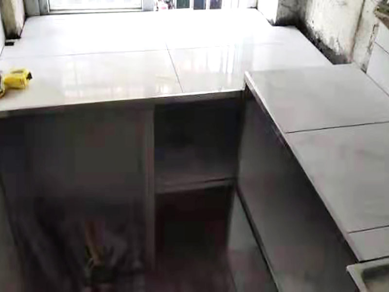 廚房磚砌櫥柜：櫥柜的水電定位時，先劃分功能區(qū)：洗菜盆區(qū)、灶臺區(qū)、切菜區(qū)、電器區(qū)，把這些區(qū)域的具體尺寸畫在墻面上，安排好進水管、排水管和各種插座的準(zhǔn)確位置。 磚砌櫥柜制作的時候先做櫥柜的圍角，可以根據(jù)自己的喜好選擇不同顏色的瓷磚來實現(xiàn)。圍角完成以后的重要工作就是用水泥和砂漿將櫥柜的底部填實，上面鋪瓷磚。同時，瓷磚豎隔板的位置按照櫥柜圖紙進行預(yù)留。 磚砌櫥柜制作好之后，我們可以根據(jù)自己喜歡的風(fēng)格選擇不同材質(zhì)的石材臺面和門板，完全不影響美觀，同時對于櫥柜內(nèi)部我們均采用不銹鋼條進行收邊，既美觀又好打掃衛(wèi)生。